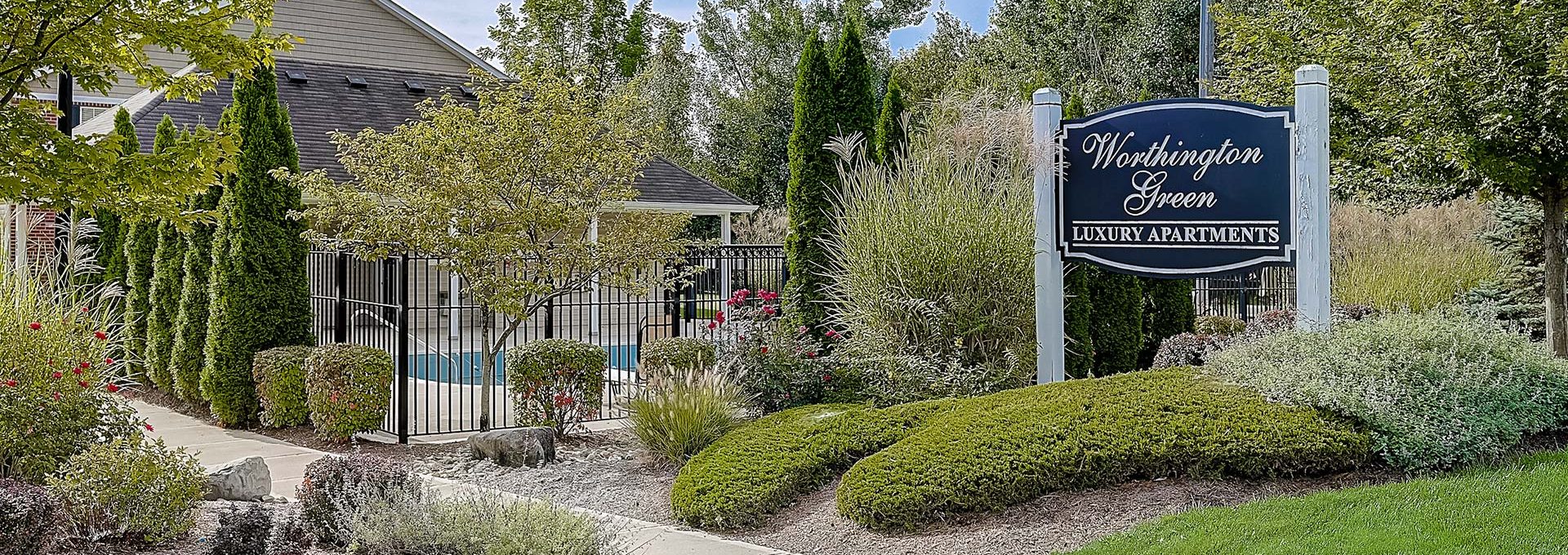 the entrance to a residential community with landscaping and trees at The Worthington Green