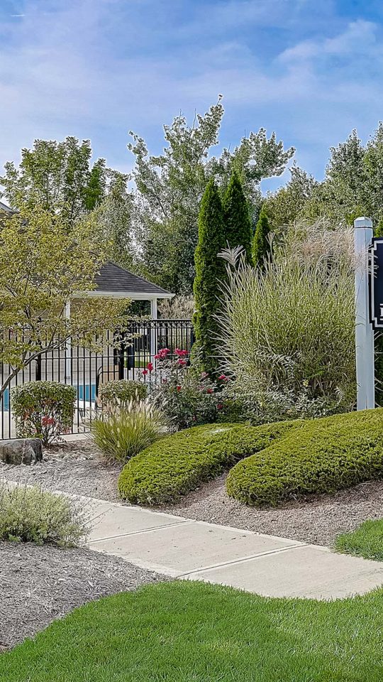 the entrance to a residential community with landscaping and trees at The Worthington Green